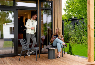 Due persone si rilassano su una terrazza in legno della Sunlodge all'Holiday Park 't Rheezerwold, Paesi Bassi.