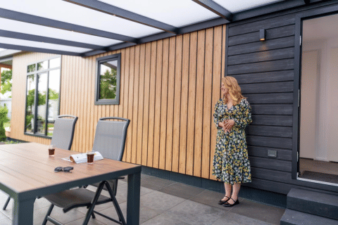 Donna in abito floreale davanti a una Sunlodge all'Holiday Park 't Rheezerwold nei Paesi Bassi.