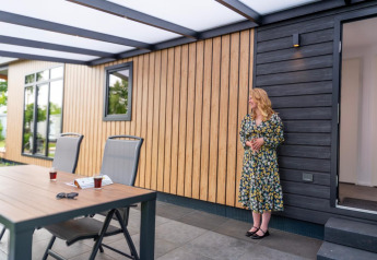 Femme en robe à fleurs devant une Sunlodge au Holiday Park 't Rheezerwold, Pays-Bas.