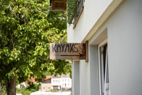 Wooden sign with 'KAYAKS' and an arrow on a building at Camping du Rivage in Diekirch, Luxembourg