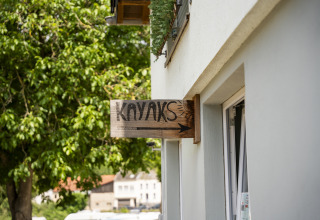 Letrero de madera con 'KAYAKS' y una flecha en un edificio en Camping du Rivage, Diekirch, Luxemburgo