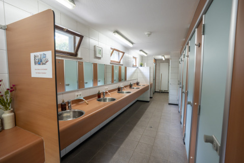 Salle de bains commune avec lavabos et miroirs au Camping du Rivage, parc de vacances à Diekirch, Luxembourg.