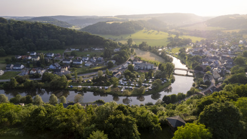 Vista aerea di Camping du Rivage a Diekirch, Lussemburgo, con fiume, ponte e paesaggio naturale.
