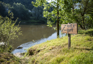 Cartello vicino all'acqua al Camping du Rivage a Diekirch, Lussemburgo, circondato da alberi verdi.