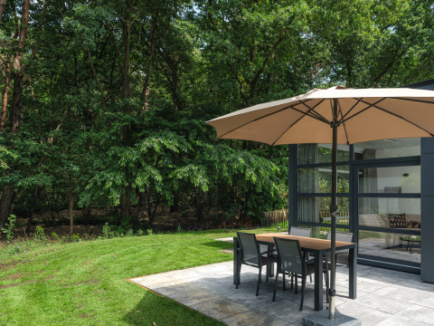 Buitenpatio met parasol en eettafel bij Bosvilla Comfort, Veluwepark de Bosgraaf, Nederland.