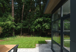 Uitzicht vanuit Bosvilla Comfort in Veluwepark de Bosgraaf, Nederland, met terras, grasveld en bos.