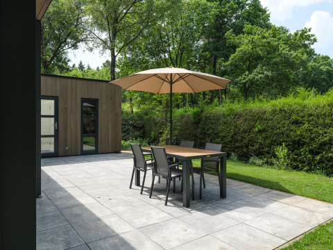 Terras aan Bosvilla Comfort in Veluwepark de Bosgraaf, Nederland, met tafel, stoelen en parasol.