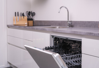 Cocina moderna en Bosvilla Comfort, Veluwepark de Bosgraaf, con lavavajillas abierto y utensilios.