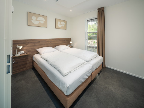 Modernes Schlafzimmer in der Bosvilla Comfort im Veluwepark de Bosgraaf, Niederlande, mit Doppelbett und schlichter Deko.