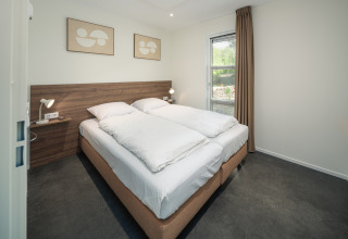 Moderne slaapkamer in Bosvilla Comfort in Veluwepark de Bosgraaf, Nederland, met dubbel bed en sobere aankleding.