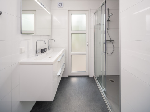 Modernes Badezimmer mit Doppelwaschbecken, Dusche und Spiegel in einer Lodge im Veluwepark de Bosgraaf, Niederlande.