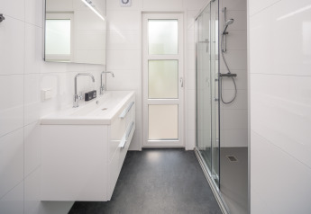 Modernes Badezimmer mit Doppelwaschbecken, Dusche und Spiegel in einer Lodge im Veluwepark de Bosgraaf, Niederlande.