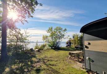 Vista lago e bosco dal Tiny Wagon al Marina Parcs Almere, Paesi Bassi, con sole e natura all’aperto.
