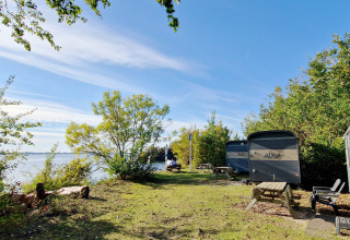 Uitzicht op Tiny Wagon huisjes bij Marina Parcs Almere, Nederland, met veel groen en water op de achtergrond.