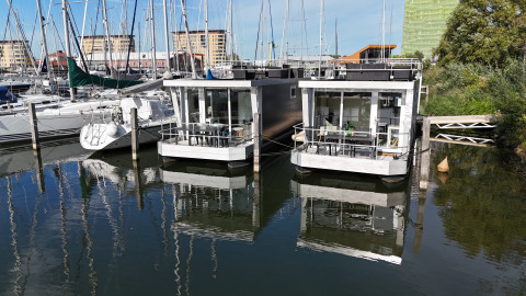 Dos modernas casas flotantes en Marina Parcs Almere, Países Bajos, rodeadas de veleros y agua.