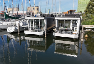 Dos modernas casas flotantes en Marina Parcs Almere, Países Bajos, rodeadas de veleros y agua.