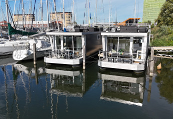 Two modern houseboats at Marina Parcs Almere, Netherlands, surrounded by sailboats and waterfront.