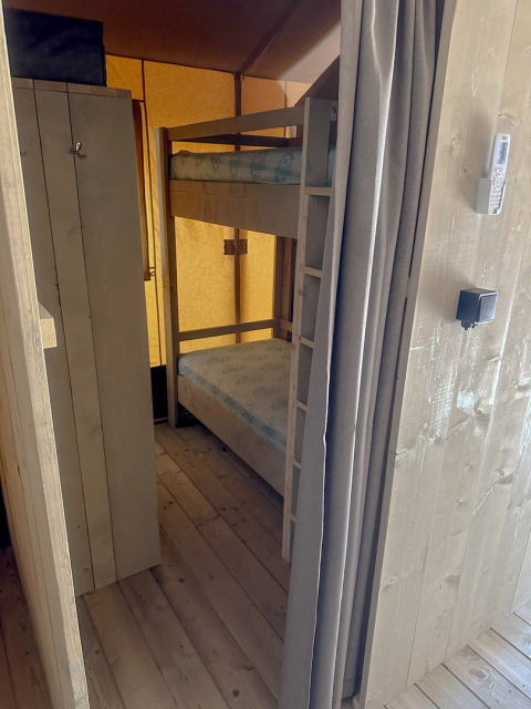 Binnenaanzicht van een safaritent met stapelbed en kast op Vilanova Park Camping in Spanje.