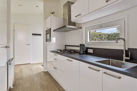 Moderne witte keuken in Natuurlodge bij Recreatiepark het Esmeer, Nederland, met raam en aanrecht.