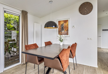 Comedor en Natuurlodge de Recreatiepark het Esmeer, Países Bajos, con decoración moderna y vista al jardín.