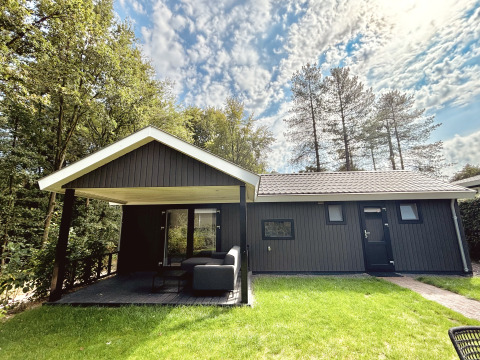 Exterior of Bos Cottage lodge at De Thijmse Berg in the Netherlands, surrounded by trees and lawn