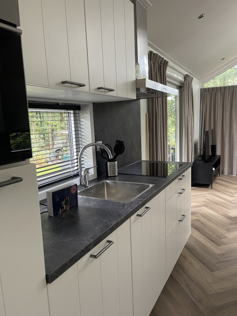 Moderne køkkeninteriør i en lys lodge på Bos Cottage, De Thijmse Berg, Holland med vindue og parketgulv.