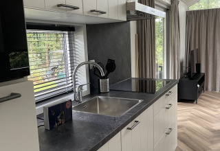 Moderne køkkeninteriør i en lys lodge på Bos Cottage, De Thijmse Berg, Holland med vindue og parketgulv.