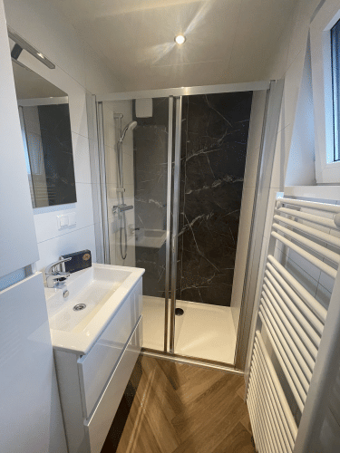 Baño moderno con ducha, lavabo, espejo y radiador en Bos Cottage, De Thijmse Berg, Países Bajos.