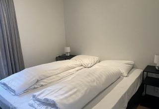 Schlafzimmer im Bos Cottage, De Thijmse Berg, Niederlande, mit Doppelbett und zwei Bettdecken.