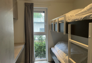 Kleines Zimmer in Bos Cottage, De Thijmse Berg, Niederlande, mit Etagenbetten und Fensterblick.