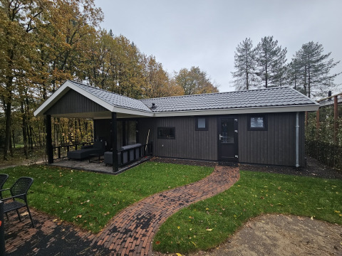 Foto del Bos Cottage lodge a De Thijmse Berg, nei Paesi Bassi, circondato da alberi e prato verde.