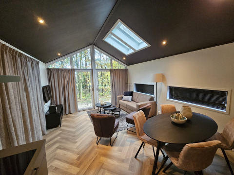 Modernes Wohnzimmer in der Bos Cottage Lodge, De Thijmse Berg, Niederlande, mit großen Fenstern.