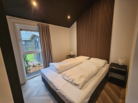 Chambre moderne à Bos Cottage, De Thijmse Berg, Pays-Bas, avec mur en bois et grande fenêtre lumineuse.