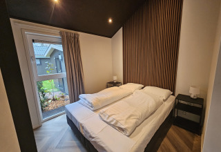 Moderne soveværelse i Bos Cottage på De Thijmse Berg, Holland, med store vinduer og elegant træpanel.