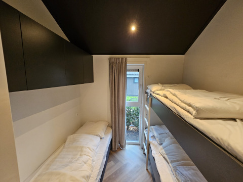 Schlafzimmer mit Einzelbett und Etagenbett in einer Bos Cottage Lodge in De Thijmse Berg, Niederlande.