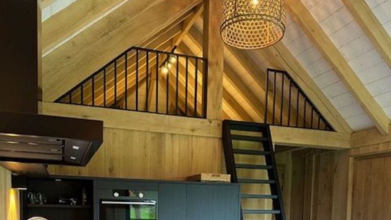 Interior of a safari tent house with wooden beams, loft, and black ladder at Beloofde Land, Netherlands.