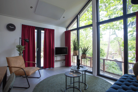 Moderne stue med store vinduer og udsigt til skov ved Eco Cottage på De Thijmse Berg i Holland.