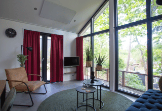 Modern living room with large windows and forest view at Eco Cottage in De Thijmse Berg, Netherlands.