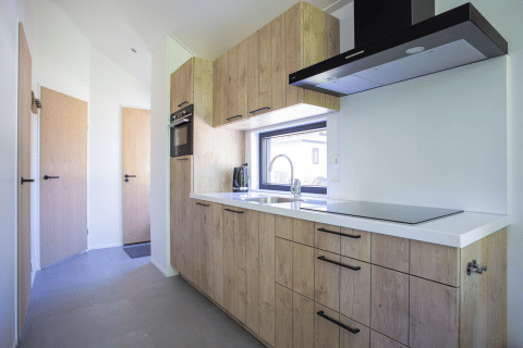 Moderne Kücheninnenausstattung mit Holzschränken und weißen Oberflächen in der Eco Cottage, De Thijmse Berg.