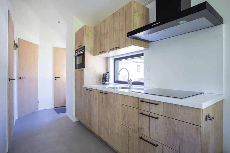 Moderne Kücheninnenausstattung mit Holzschränken und weißen Oberflächen in der Eco Cottage, De Thijmse Berg.