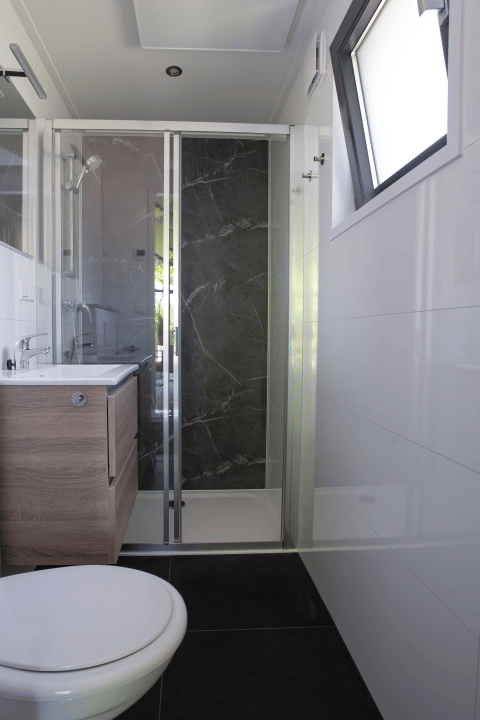 Modernes Badezimmer mit Dusche, Holzwaschbecken und Fenster in der Eco Cottage, De Thijmse Berg, Niederlande.