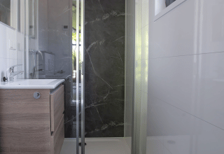 Modern bathroom with shower, wood vanity, and window at Eco Cottage, De Thijmse Berg, Netherlands.