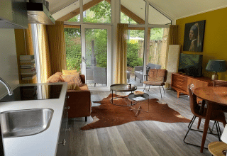 Bright, modern living room at Eco Cottage, De Thijmse Berg, Netherlands, with glass doors and wood décor.