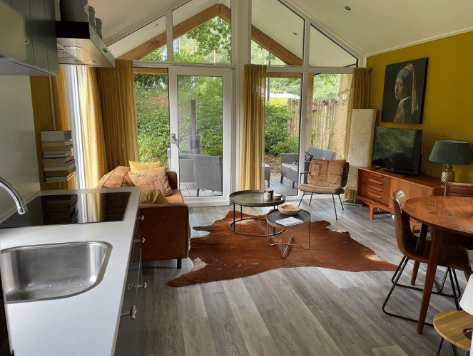 Acogedora sala moderna en Eco Cottage, De Thijmse Berg, Países Bajos, con ventanales y muebles de madera.