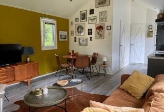 Stue i Eco Cottage på De Thijmse Berg med retro møbler, gul væg, billedvæg og grønne omgivelser.