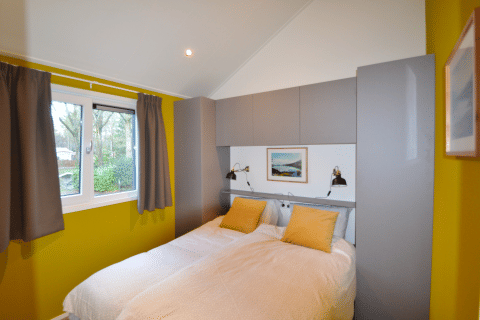 Schlafzimmer in der Eco Cottage auf De Thijmse Berg, Niederlande, mit gelben Wänden und Doppelbett.