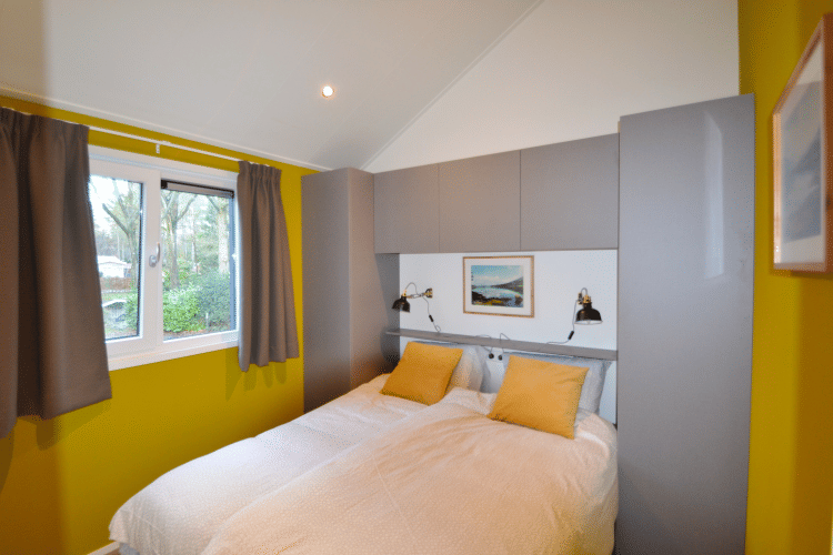 Schlafzimmer in der Eco Cottage auf De Thijmse Berg, Niederlande, mit gelben Wänden und Doppelbett.