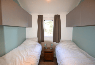 Soveværelse med to enkeltsenge og lyse gardiner, Eco Cottage, De Thijmse Berg, Holland.