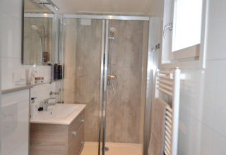 Moderne badeværelse med brusekabine, toilet, håndvask, spejl og vindue i Eco Cottage, De Thijmse Berg, Holland.