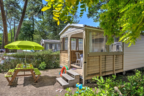 Tenda safari Cabane Nature al Flower Camping Au Bois Des Biches in Francia, con tavolo da picnic e ombrellone verde.